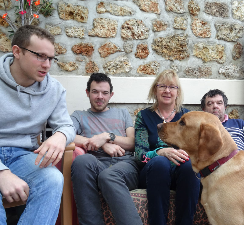 L'ensemble de la famille de Jasko est réuni sur le canapé. Jasko est assis par terre et regarde fixement l'un des deux enfants.