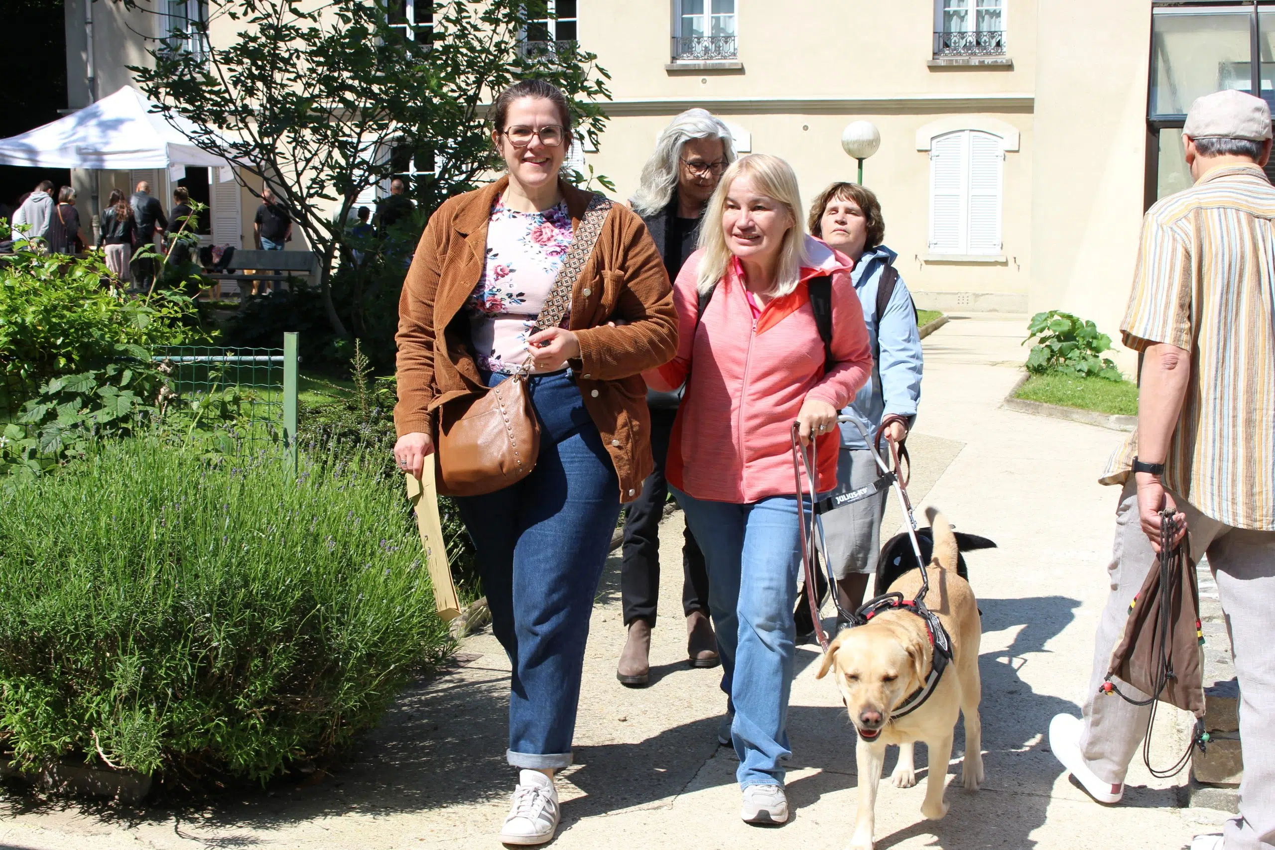 Corinne avec son chien guide et une famille d'accueil la guidant