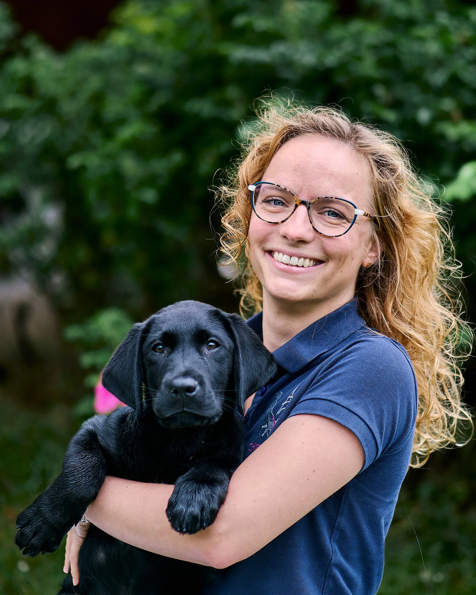 Cécile posant avec Viper, chiot labrador noir