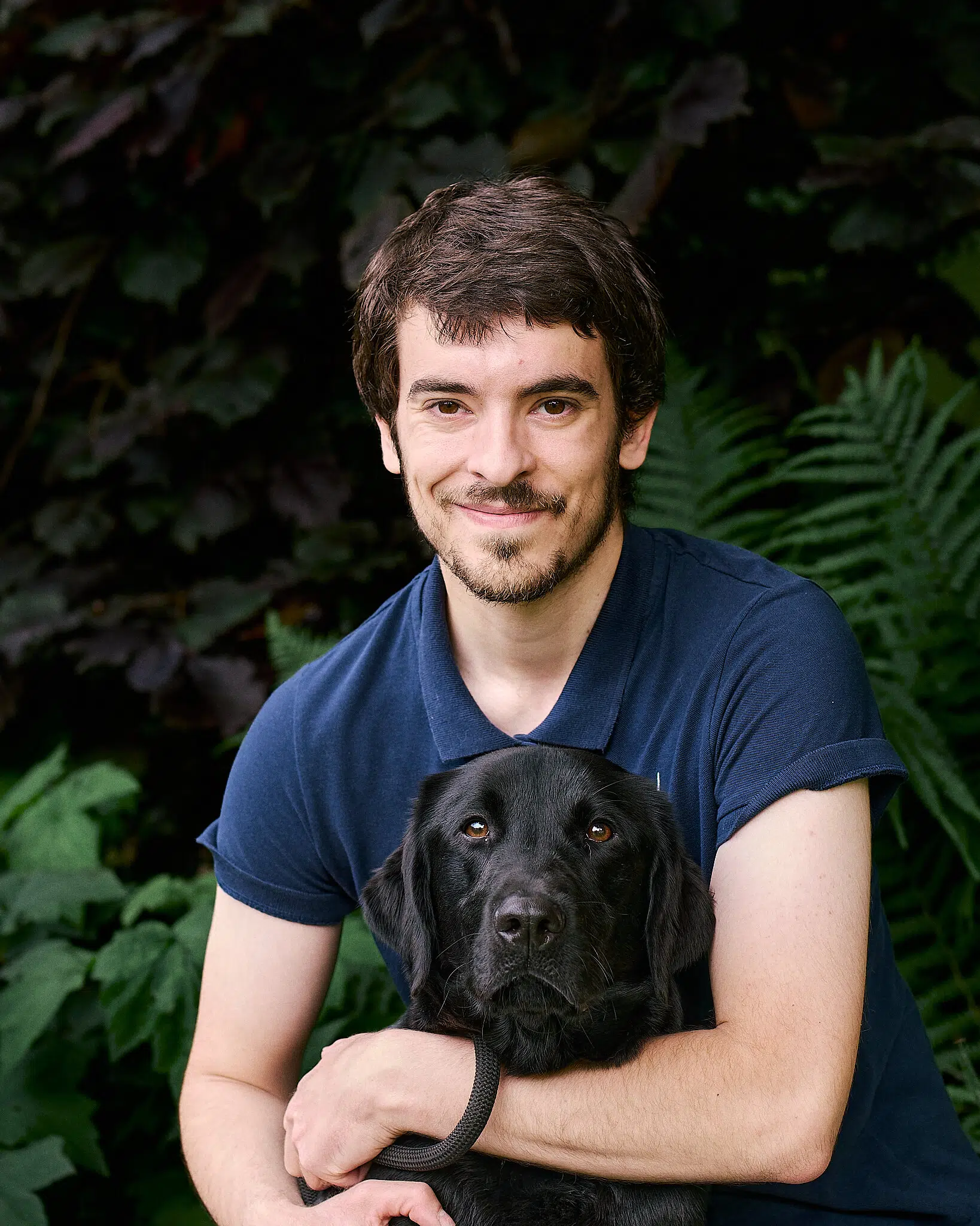 Elie posant avec Toku, labrador noir